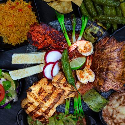 Molcajete bowl with grilled steak, chicken, shrimp, and sausage.