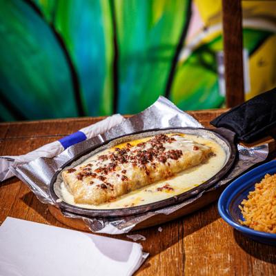 Chimichanga topped with cheese sauce and chorizo, served in a hot skillet.