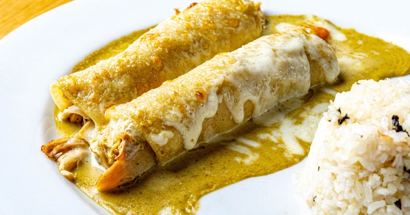 Two chicken enchiladas with green salsa and melted cheese