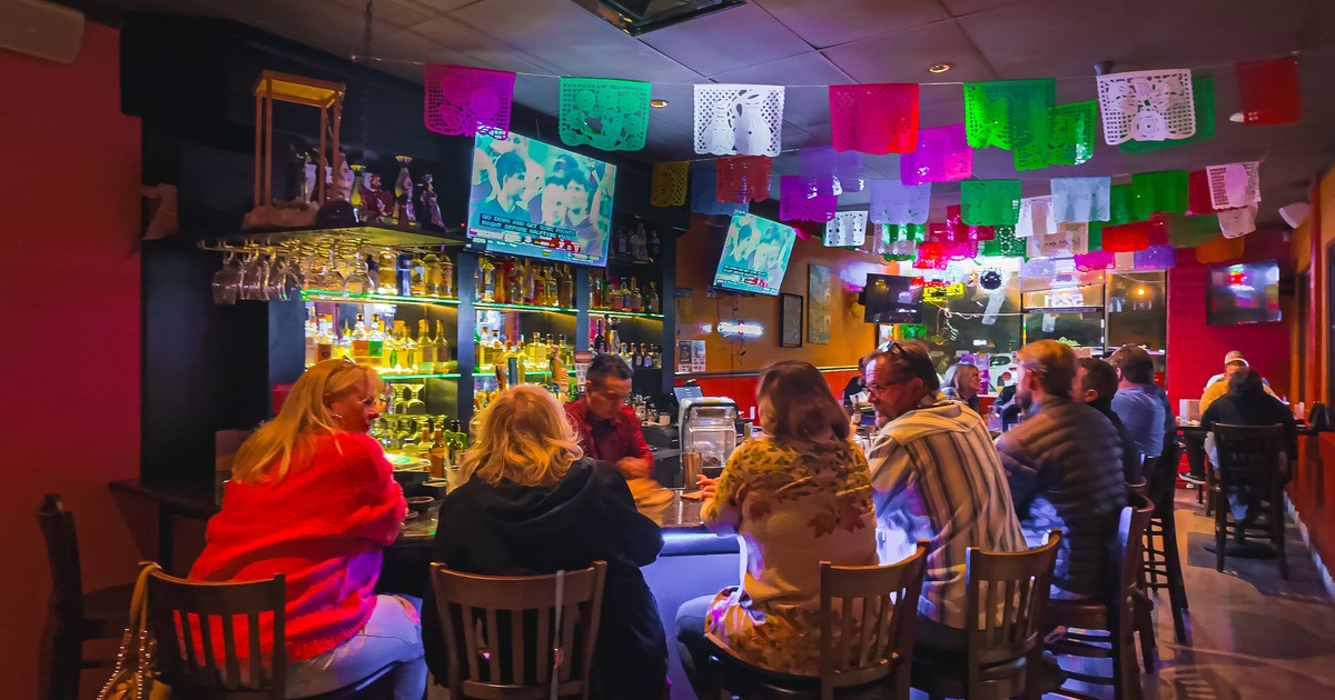 Interior, bar, bar stools, drink rack, screen above, guests, bartender