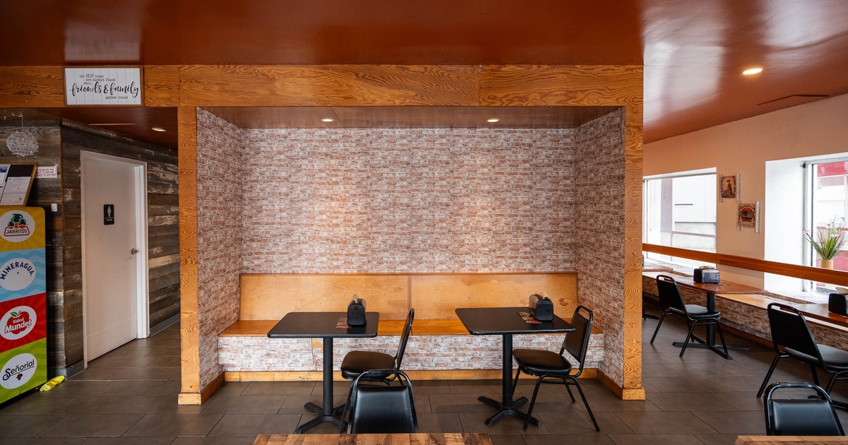 Cozy restaurant interior with brick wallpaper, wooden booths, and black chairs