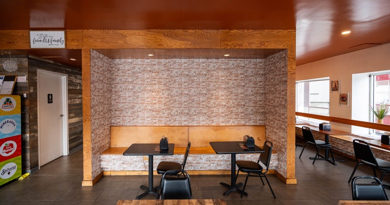 Cozy restaurant interior with brick wallpaper, wooden booths, and black chairs