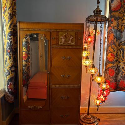 Vintage wooden cabinet beside a colorful mosaic floor lamp.