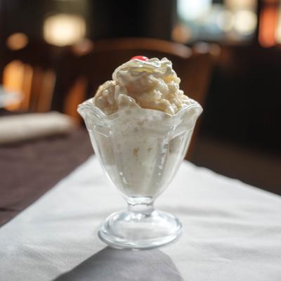 Rice Pudding topped with whipped cream and a cherry.