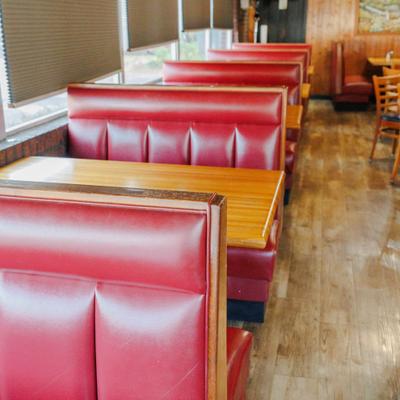 Interior with several rows of red, booth-style seating with tables.