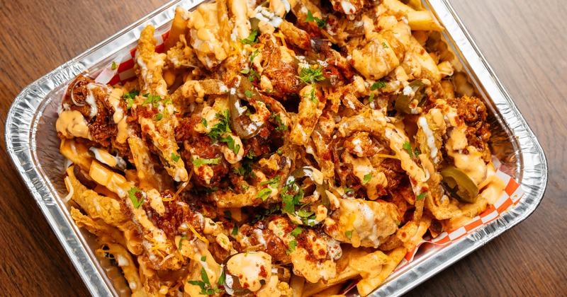 Loaded fries, with onion rings, fried pickles, dumplings, cheese, scallions, bacon, and sauce