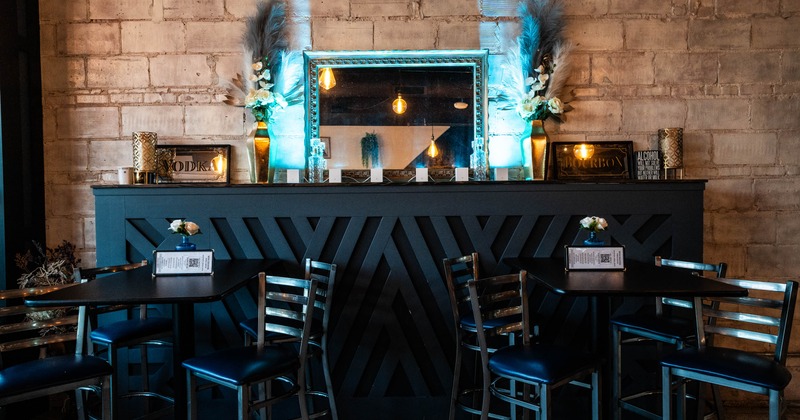Chairs and tables, textured brick wall, decorative mirror and illuminated teal lighting
