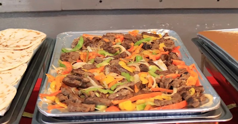 Beef fajitas with peppers and onions in a catering tray served with flour tortillas