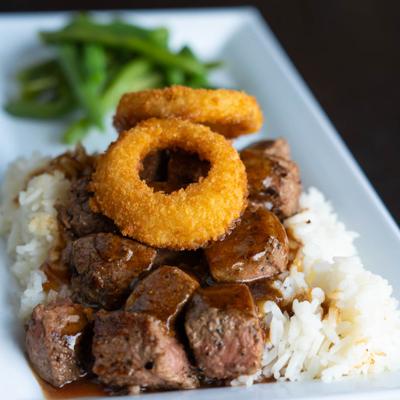 Top Sirloin over white rice, with onion rings and green beans.