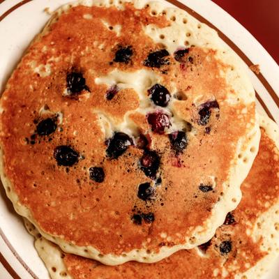 Stack of blueberry pancakes on a white plate with brown stripes.