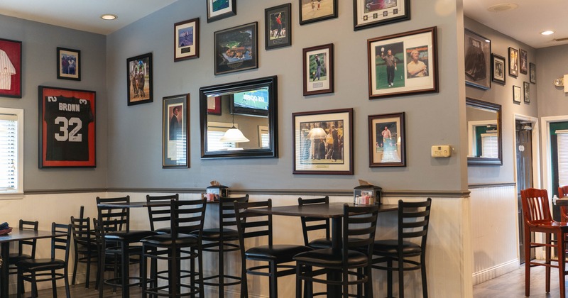Interior with sports-themed decor, numerous framed pictures, black tables and chairs