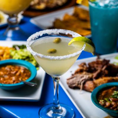 Mexican Martini cocktail served on the table with various dishes and drinks.