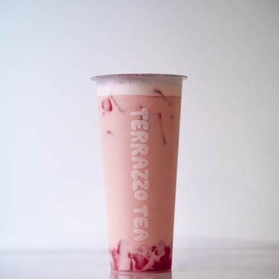 A tall clear cup filled with iced pink bubble tea, with Terrazzo Tea written on it.