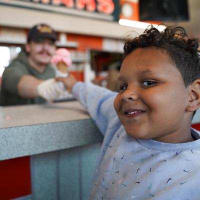 cute kid waiting on strawberry ice cream cone.