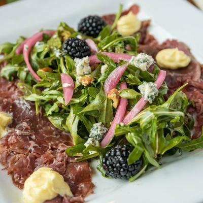 Beef Carpaccio, with arugula, blue cheese, walnuts, blackberries, pickled onion, and garlic aioli.