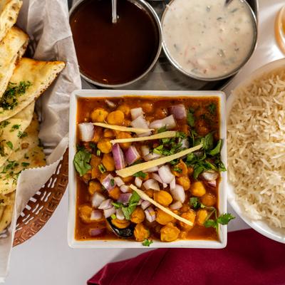 Chana Masala, garlic naan, basmati rice, chutney, and Mango Lassi, top down view.