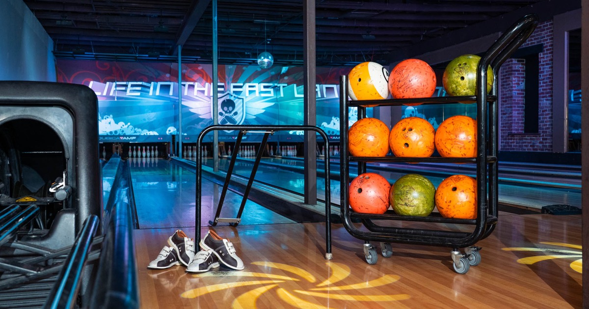 Bowling lane with a rack of bowling balls and bowling shoes placed on wooden floor