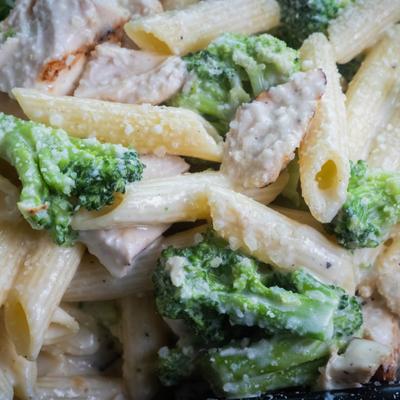 Close-up of chicken alfredo pasta with broccoli and creamy sauce.