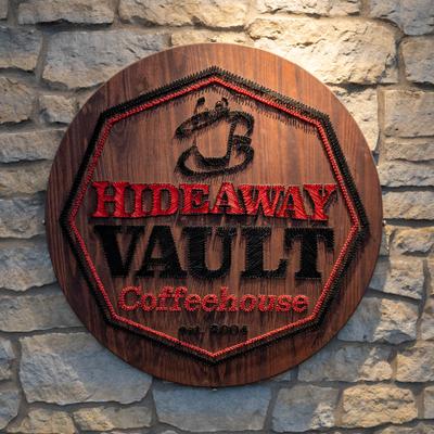 The logo for The HideAway Vault Coffeehouse on a stone wall.