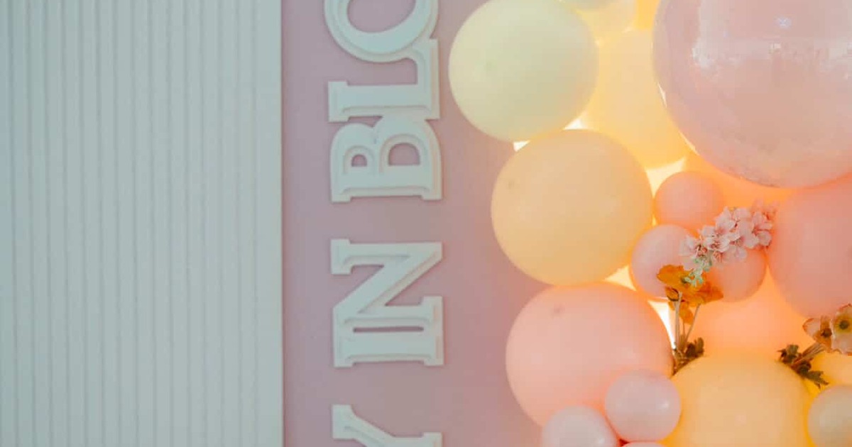 Pastel balloon display beside vertical celebration sign