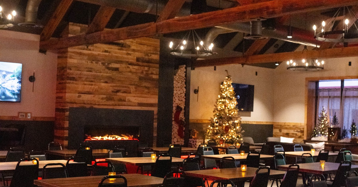 Interior with wooden beams, stacked wood-panel fireplace and a Christmas tree