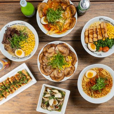 Multiple bowls of ramen served alongside appetizers and drinks.