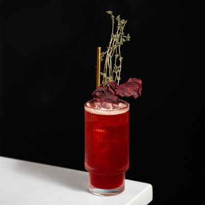 Cocktail in a highball glass, garnished with thyme spring.