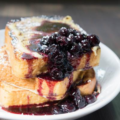 French toast topped with powdered sugar and berry sauce, close up.