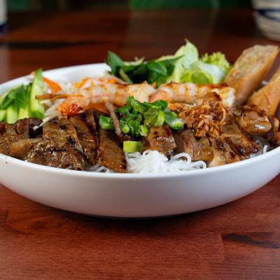 Vietnamese vermicelli noodle salad with grilled pork, shrimp skewers, and crispy spring rolls.