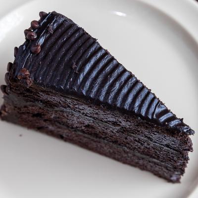 Chocolate Layer Cake with ridged frosting on top, resting on a white plate.