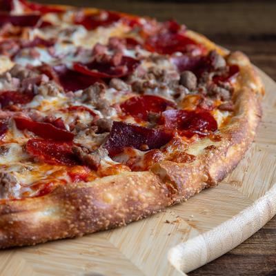 Meat Lover pizza on a wooden serving board.