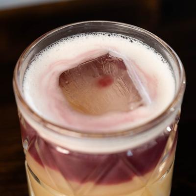 Close-up of a cocktail that has layered hues of red and beige, creating an elegant look.