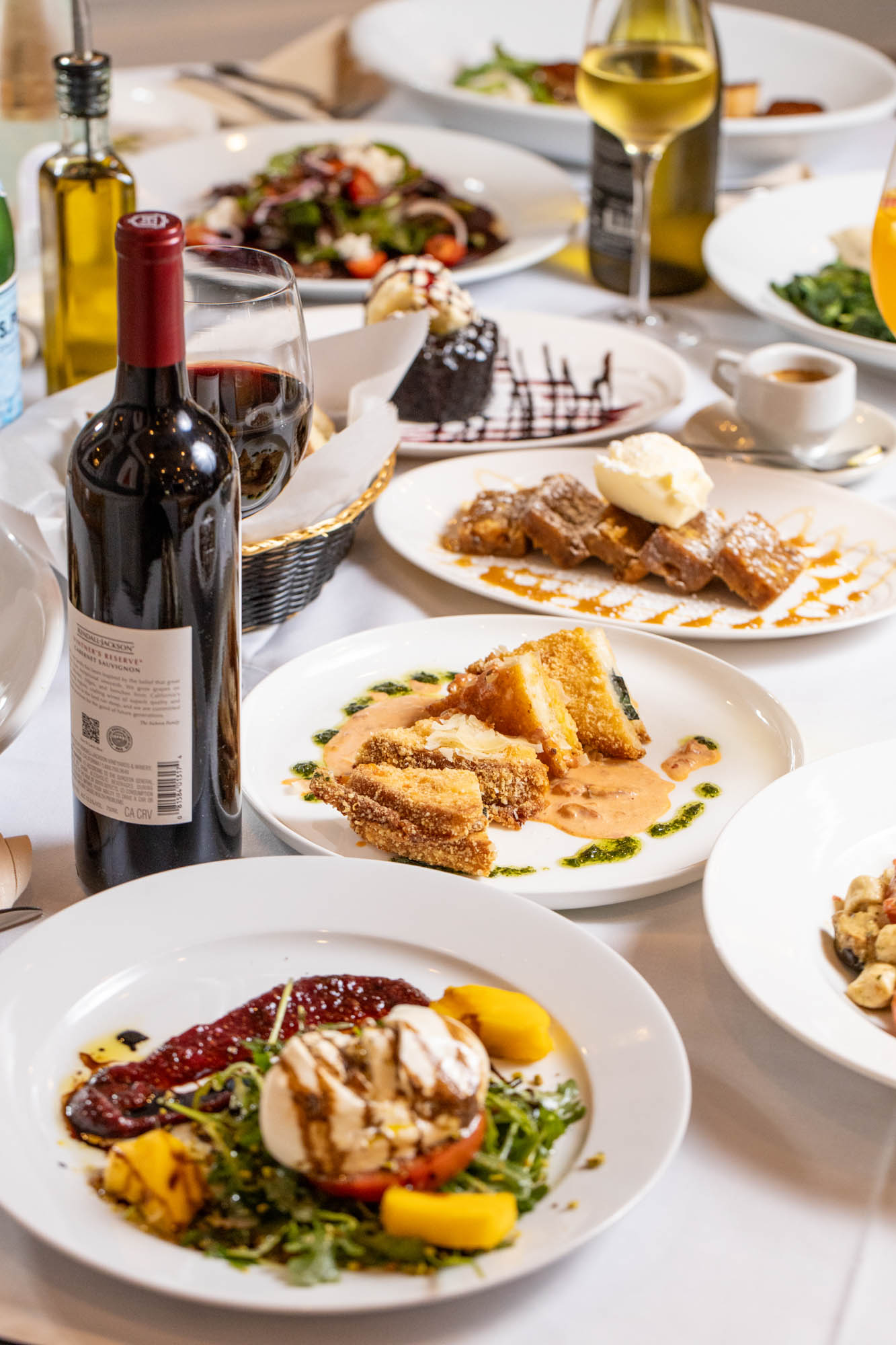 a table filled with a variety of dishes and a bottle of red wine