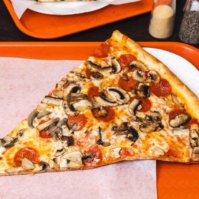 A slice of pizza with pepperoni and mushrooms on a tray.