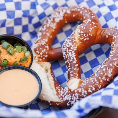 A pretzel served with cheese dip and a small salad.