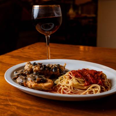 Chicken with sauteed mushrooms, spaghetti in tomato sauce, and a glass of red wine.