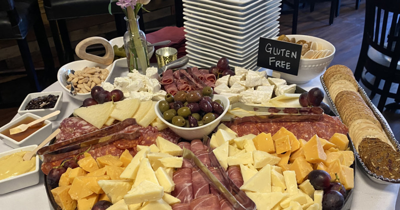 Charcuterie table with cheese, olives, crackers, almonds and condiments