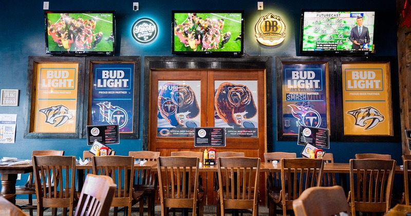 Interior with tables lined up and chairs, TV sets, and posters on the wall