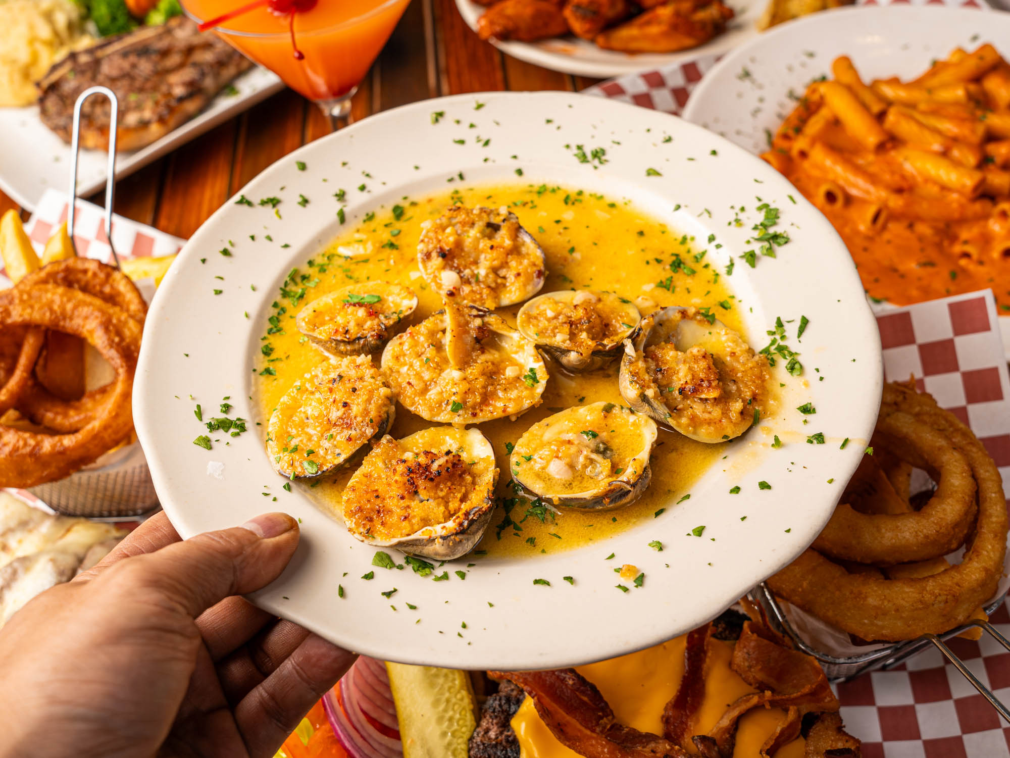 A hand holding a baked clam plate