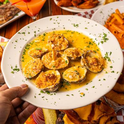 A hand holding a baked clam plate.