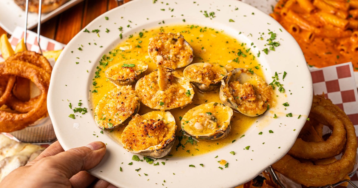 A hand holding a baked clam plate