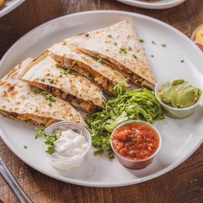 Chicken quesadilla served with lettuce, salsa, guacamole, and sour cream
