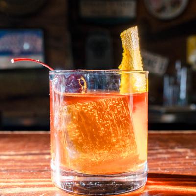 Old Fashioned cocktail garnished with orange peel and a cherry.