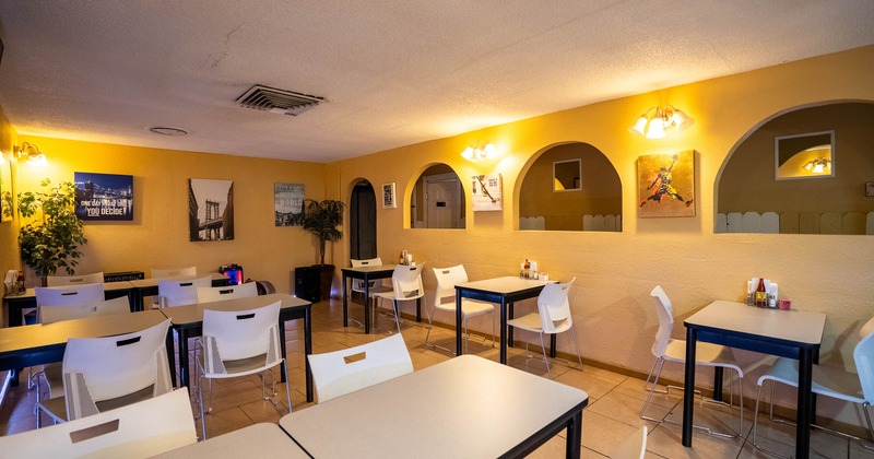 Cozy dining area with mustard yellow walls, tables with white chairs