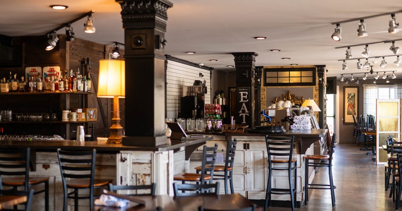 Interior, seating area, tables and chairs with a bar in the back