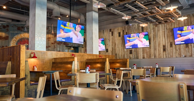 Rustic sports restaurant interior with wooden seating, industrial lighting, and several televisions