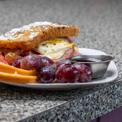 Monte Cristo sandwich served with grapefruit, grapes, and syrup.
