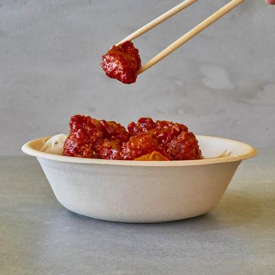 Sweet and sour chicken bite taken with chopsticks.