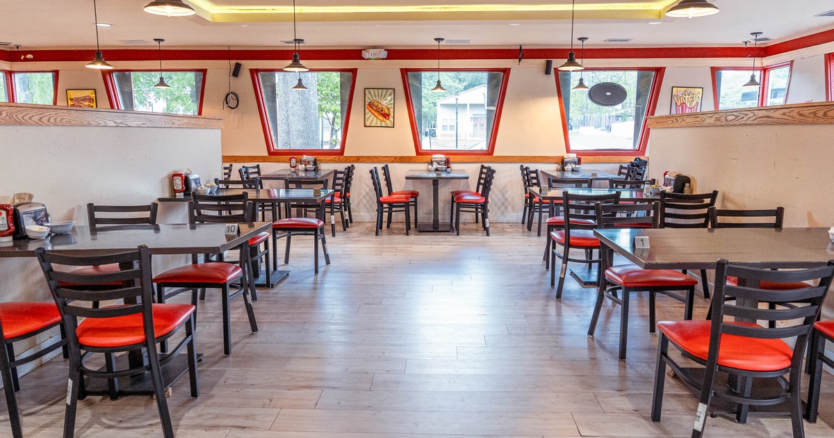 Interior - tables and chairs, featuring red accents and large windows.