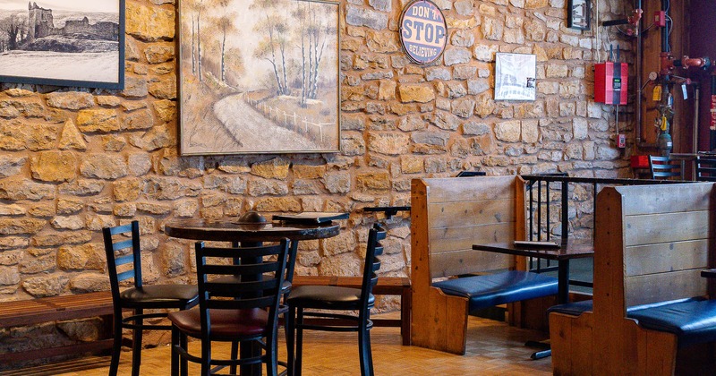 Interior, tables and chairs near stone wall with pictures